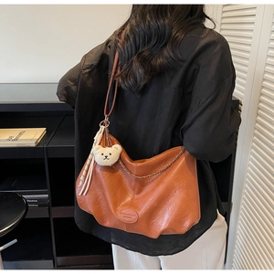 Détail d'un grand sac cabas en similicuir caramel avec charm ours porté par un mannequin