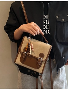 Vintage beige and brown dual-tone backpack with metallic buckles and beaded charm