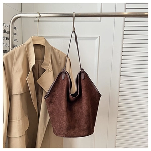 Detailed view of dark brown frosted suede hobo tote bag hanging on a minimalist metal stand