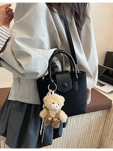 Black canvas and leather mini tote bag with cute teddy bear charm on model shoulder