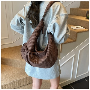 Close-up of brown plaid crescent bag with wide strap and side drawstring details