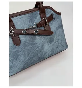 Detailed macro of vintage denim handbag with brown leather trim and silver metal hardware