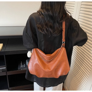 Détail du sac hobo marron avec large bandoulière et chaîne métallique décorative