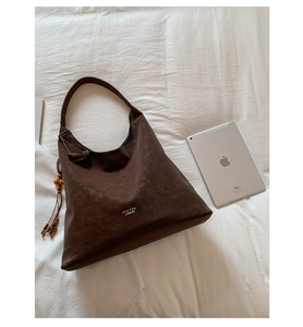 Detail view of large dark brown retro tote bag with wooden bead charm and brand logo