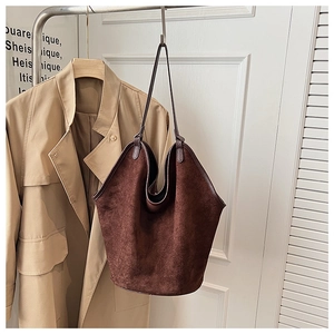 Close-up of deep brown suede tote bag texture with leather edge trim and reinforced strap