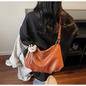 Détail du sac cabas en similicuir caramel avec bandoulière chaîne et breloque petit ourson
