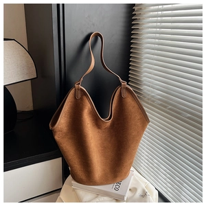 Detailed view of brown suede hobo tote bag with wide shoulder strap in minimalist setting
