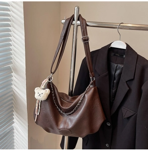 Détail du sac hobo en cuir PU marron foncé avec chaîne en métal et breloque ours peluche