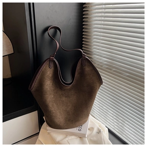Close-up of matte brown suede bucket bag with leather piping and refined texture