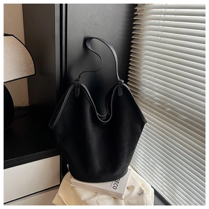 Macro detail of black matte suede bucket bag showing texture under shutter light shadows