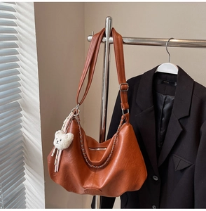 Détail du sac hobo en cuir PU orange avec chaîne argentée et breloque ours