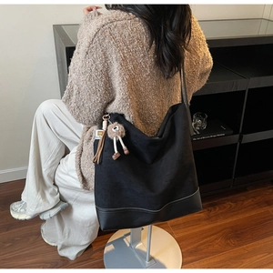 Detailed back view of a black canvas tote bag with a brown plush toy pendant accessory