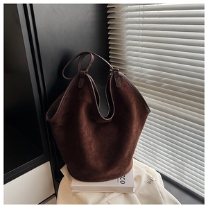 Macro detail of dark brown matte suede bucket bag texture with leather piping trim