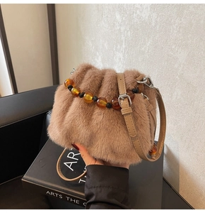Detail der Plüsch-Eimertasche mit Bernsteinperlengriff und verstellbarem Ledergurt