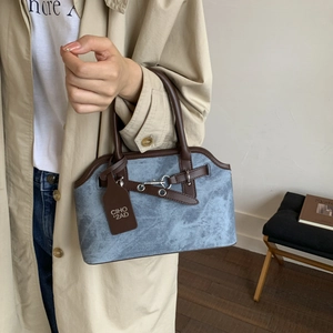 Detail of blue denim and brown leather handbag with silver metallic buckle