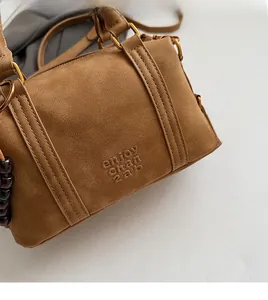 Detail of brown suede Boston bag featuring gold hardware and embossed lettering