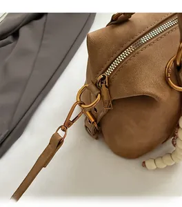 Detail of premium golden hardware and bead charm on brown suede vintage handbag