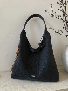 Vintage distressed black leather tote bag with a wooden bead charm and minimalist logo
