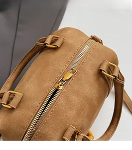 Close-up of golden zipper and lychee texture on brown Boston handbag for women