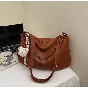 Détail du sac hobo marron caramel avec chaîne en métal et breloque ours en peluche