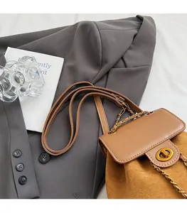 Close-up of brown bucket bag showing suede texture, gold turn-lock, and chain strap