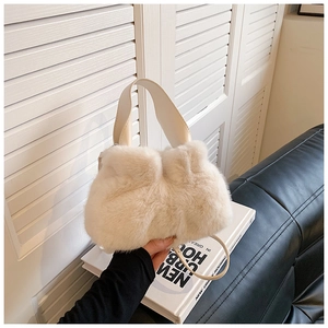 Détail de la texture douce en fausse fourrure crème et de la poignée en cuir du sac