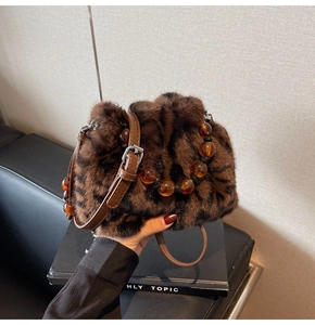 Detailaufnahme der Leoparden-Kunstpelltasche mit bernsteinfarbenem Perlengriff und Lederriemen