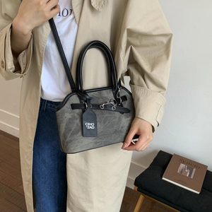 Gray textured crossbody bag with black handles styled with a beige trench coat