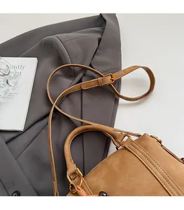 Detail of vintage brown suede Boston bag featuring gold metal buckles and slim shoulder strap