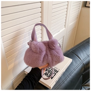 Détail d'un sac seau en fausse fourrure violette avec pompons et anse en cuir