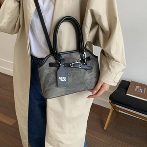 Close-up of retro gray crossbody bag with black contrast trim and silver metallic buckle