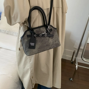 Detail view of retro grey suede crossbody bag with leather handle and branded tag