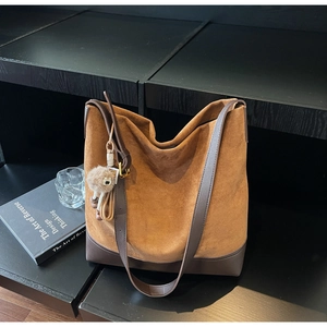 Detail of vintage brown suede bucket bag with leather trim and plush tassel charm
