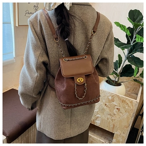 Detail of a brown suede and leather mini backpack with gold chain straps on a model