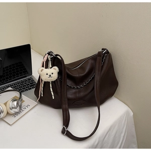 Détail du sac cabas marron foncé avec chaîne argentée, ourson en peluche et fermeture éclair