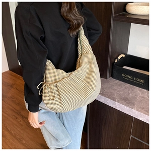 Detail of checkered crescent bag with decorative side bow and textured fabric finish