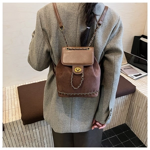 Detail of vintage brown suede backpack with gold chain trim and leather flap closure