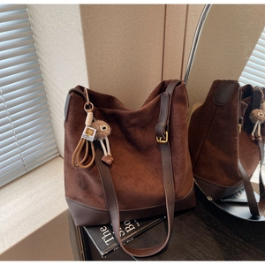 Detail view of large dark brown suede tote bag with teddy charm and adjustable strap