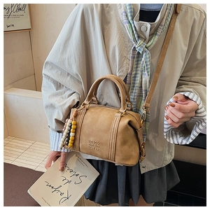 Detail view of a vintage brown leather crossbody bag with wooden beads on a model