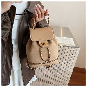 Detail of a chic beige bucket backpack with gold chain straps and metal twist lock