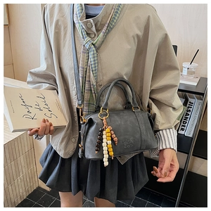 Detail of grey-blue Boston bag featuring colorful beaded charm and soft embossed texture
