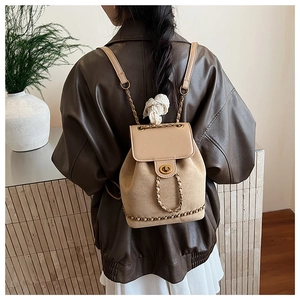 Close-up of beige suede mini backpack featuring gold chain straps and metal twist lock