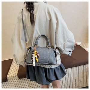 Close-up of grey matte PU leather bag with logo embossing and colorful beaded charm