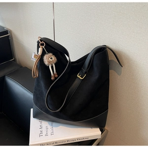 Detail of black suede tote bag with leather trim and decorative fur pom-pom charm