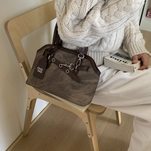 Close-up of vintage brown leather handbag with silver horsebit buckle and brand tag
