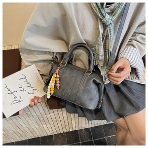 Detail of grey vintage Boston bag with embossed logo and beaded tassel charm
