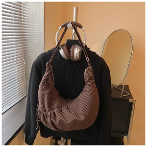 Detailed view of brown checkered crescent bag with drawstring texture in a cozy setting