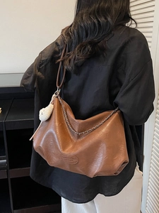 Grand sac bandoulière marron rétro avec chaîne en métal et peluche sur un modèle