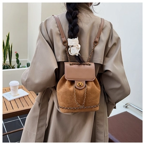 Detail of tan suede backpack with gold twist lock and metal chain on outdoor model