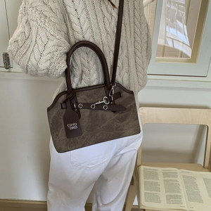 Brown vintage suede bag with metal ring buckle shown being carried by a model